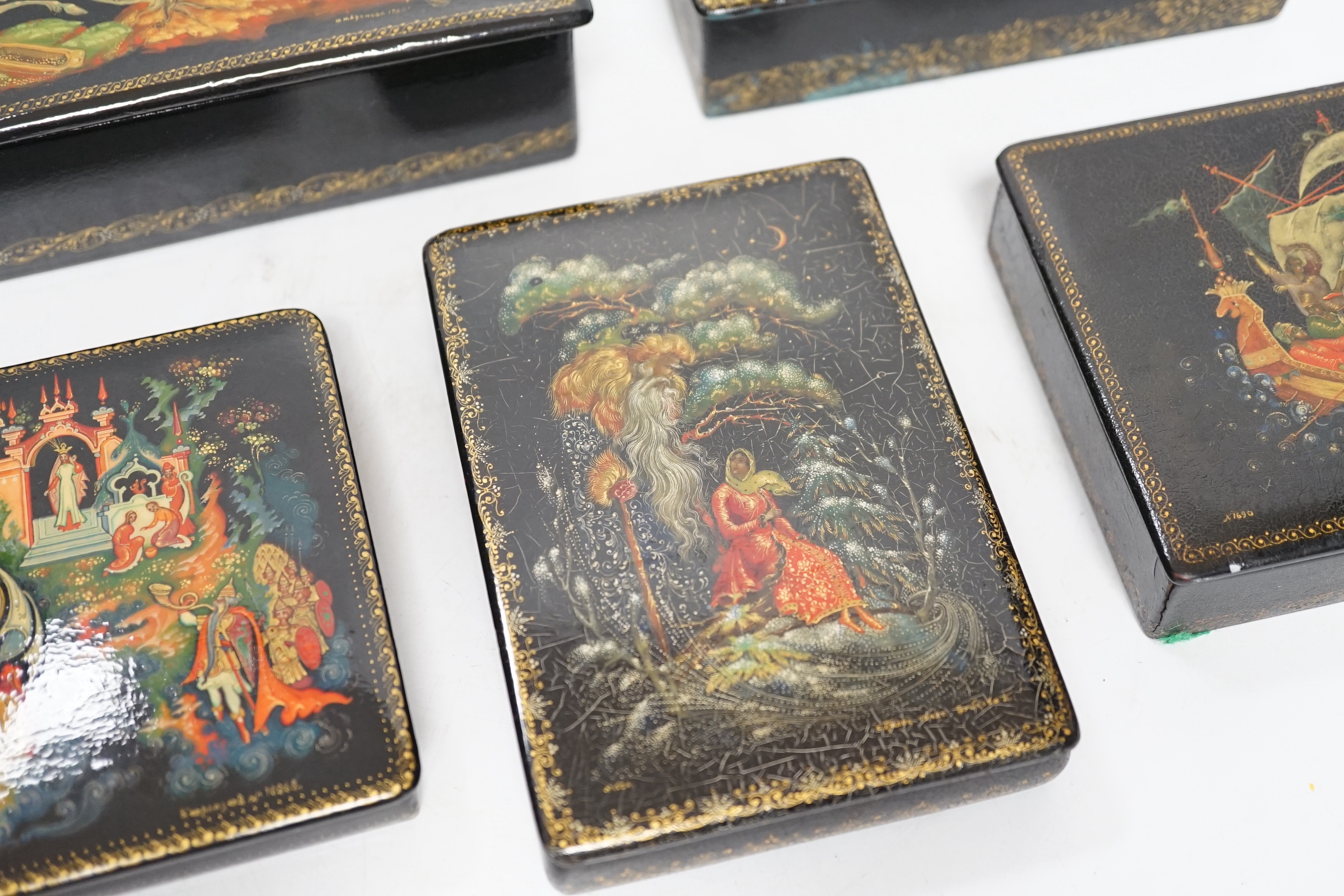 Five Russian Palekh lacquer table boxes, each painted with figures from legend, each signed by the artist, the largest 17 cm wide